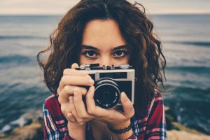 Girl taking a photo at sea with a film camera